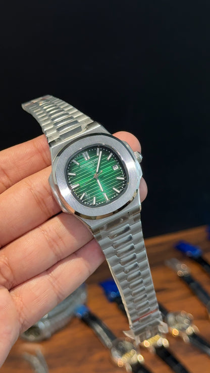 Silver watch with green face held in a hand against a blurred background